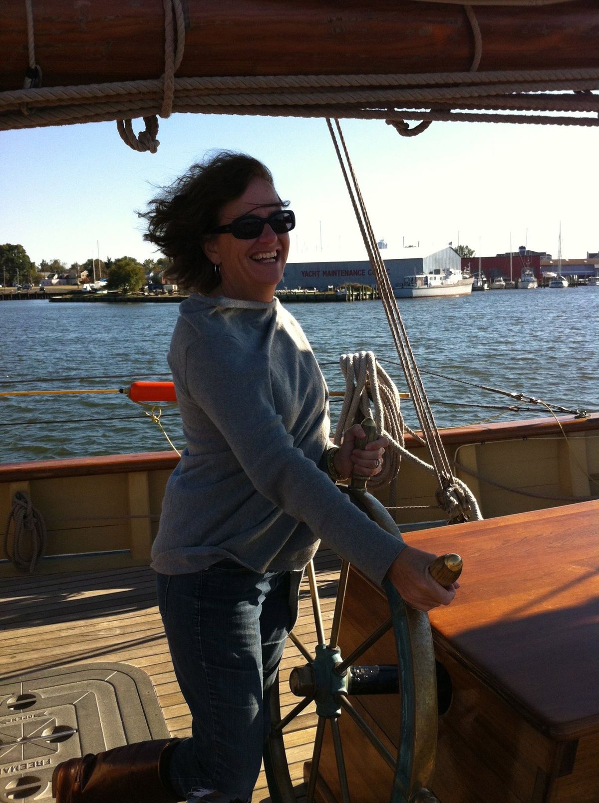 Ann Jackman Hynes laughing at the wheel of a sailing ship.