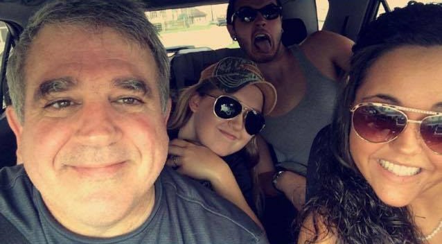 Hank Jacoby smiling in a car selfie with his family.